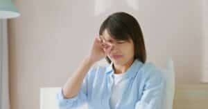 Young woman rubbing her sensitive eyes, in need of testing and diagnosis