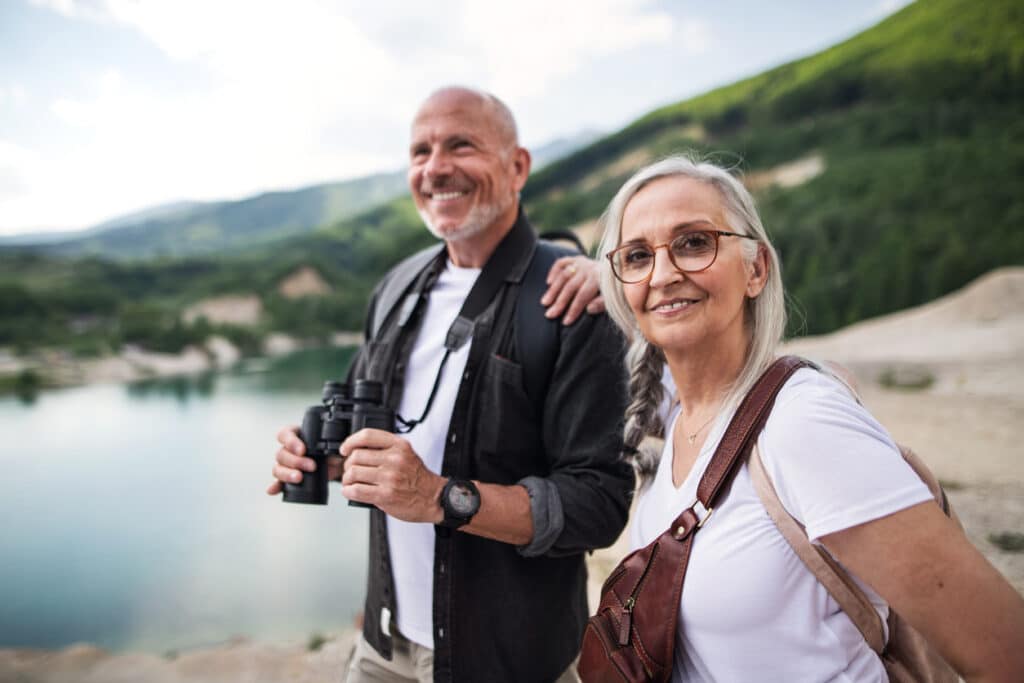 Happy senior couple on hiking trip on summer holiday, using binoculars. Eye Health in Dallas & Richardson, TX