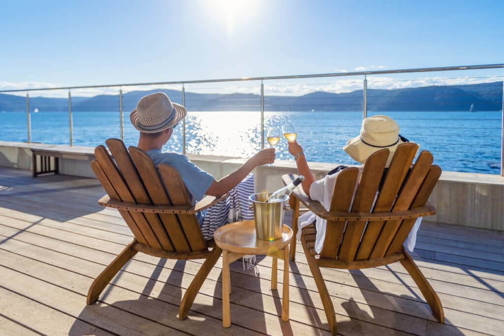 Couple relaxing and drinking wine on deck chairs in an over water bungalow. Home
