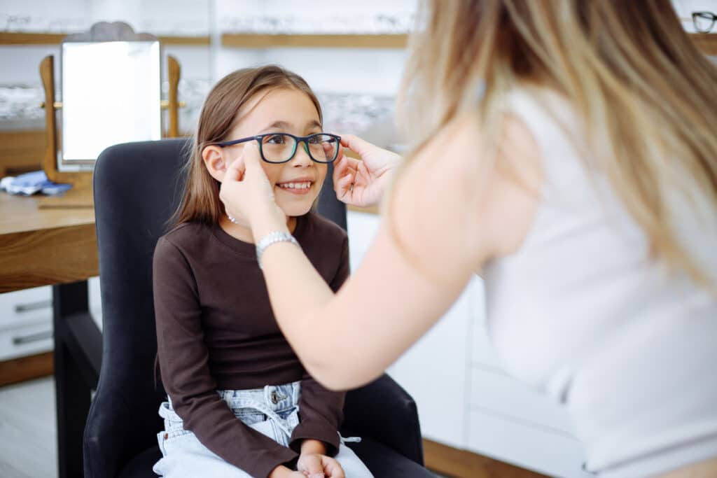 Young girl trying on eyeglasses at an optical store Young girl trying on eyeglasses at an optical store